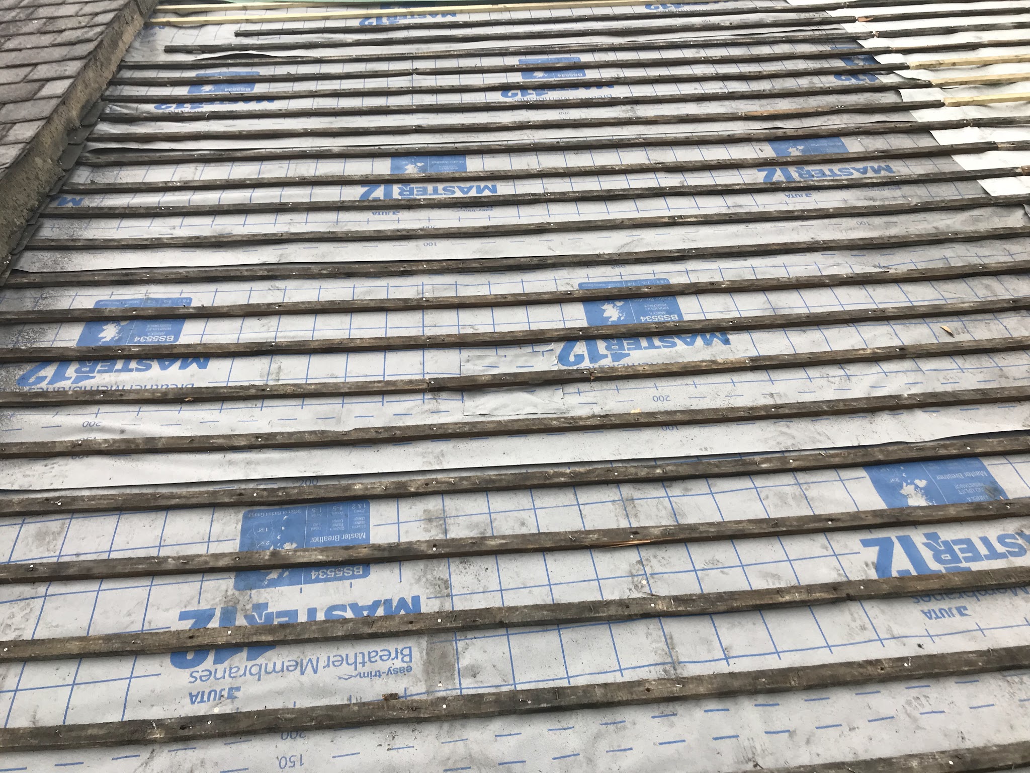 Close-up of breather membrane laid across a roof under rows of battens